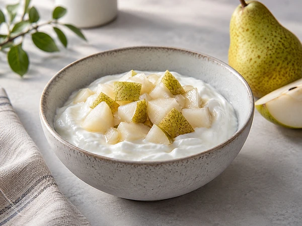 Schale mit cremigem Skyr, warmen Birnenwürfeln und einer Prise Zimt